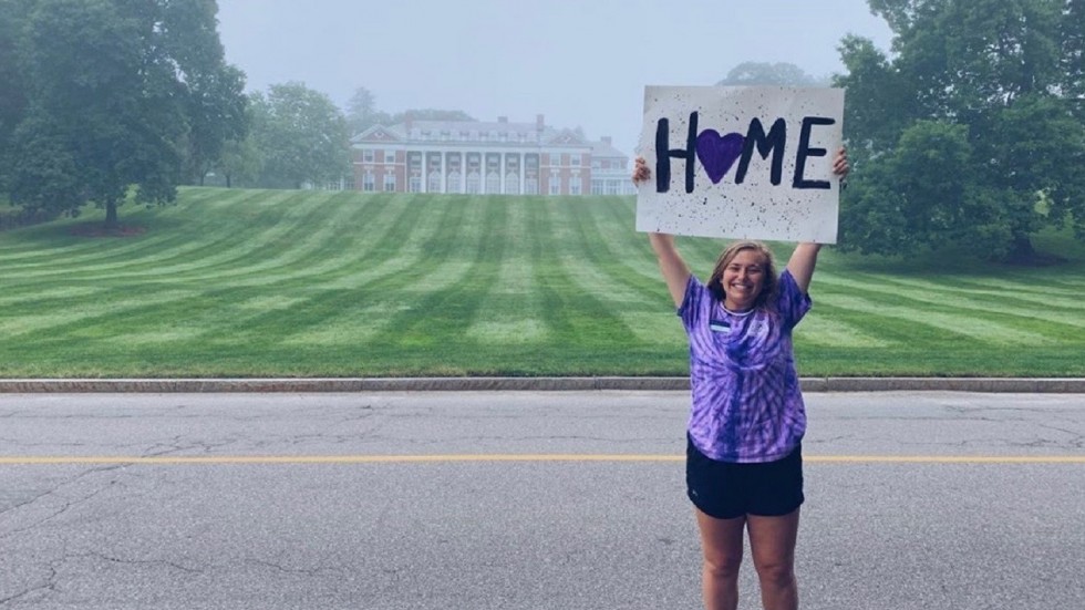 Student holding home sign