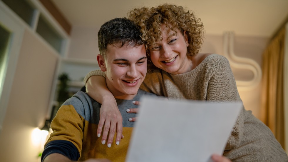 Student reading acceptance letter with his mom