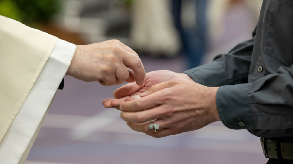 Priest's hands offering communion