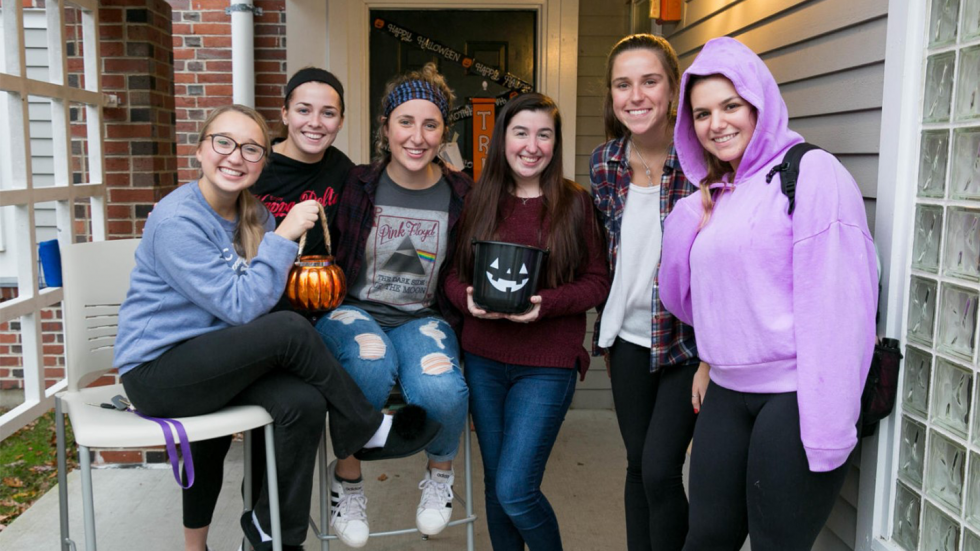 Students in front of courts with trick or treat candy bowls.