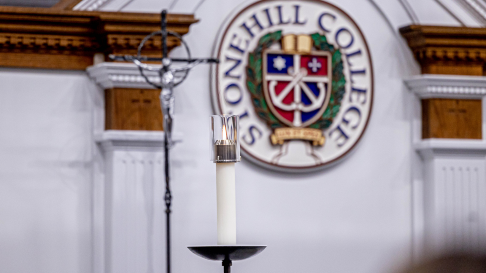 Crucifix and candle in front of Stonehill insignia