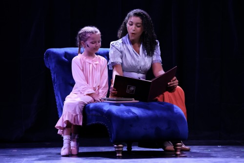 Playing the part of "Nanny," Ariana Barbosa ’27 reads a bedtime story to a child in a scene from "Murder on the Orient Express."