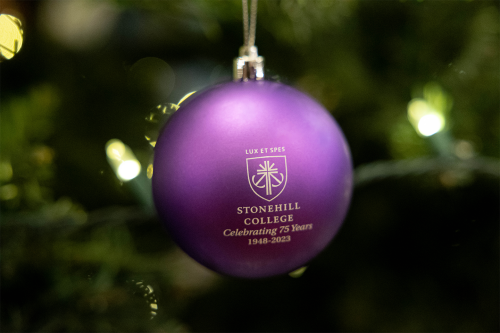 Purple Christmas ornament that reads Stonehill College Celebrating 75 Years 1948-2023