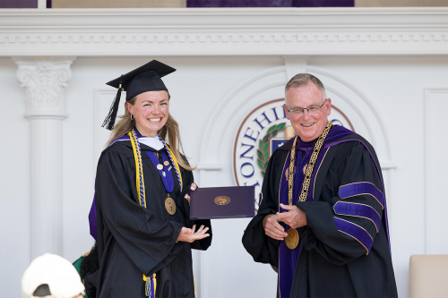 Graduate receiving diploma from Fr. John