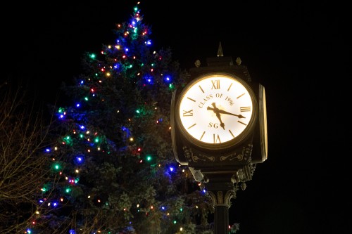 Clock on quad in front of tree with Christmas lights.