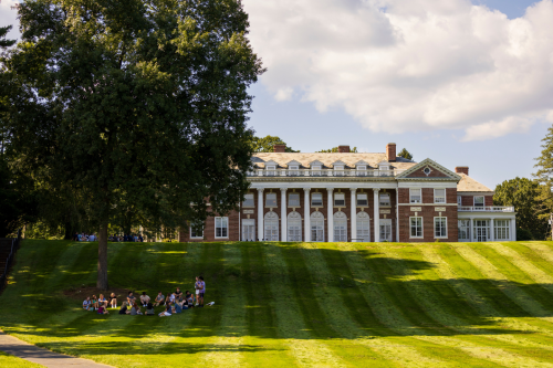 Students sitting in circle by tree in front of Donahue Hall.