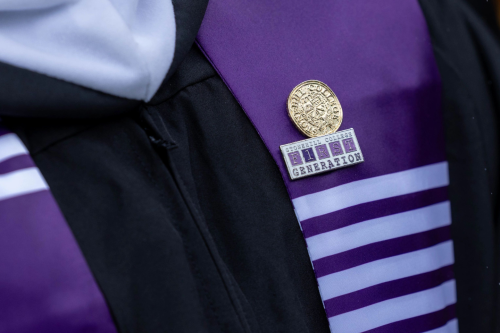 Two pins on a graduation sash, one that reads "Stonehill College First Generation."