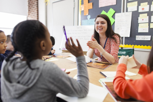 Teacher chatting with children in classroom.