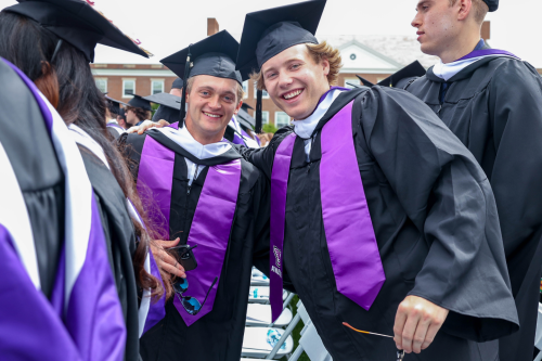 Two students in Commencement regalia, smiling