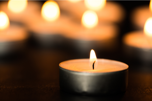 Lit candle glowing against a dark background.