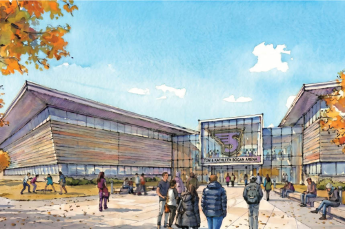 A group of people are gathered outside a modern building labeled "Tom & Kathleen Bogan Arena" on a sunny day with autumn foliage.