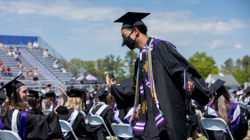 Outgoing Student Government Association President Abe Medeiros ’21 high fives a fellow graduate after receiving his diploma.