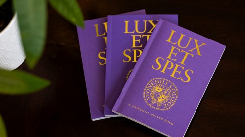Three copies of Lux et Spes Prayer book fanned out on table.