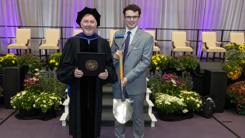 Class president holding Ames shovel with Professor Rob Rodgers after Convocation.