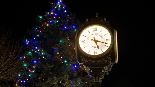 Clock on quad in front of tree with Christmas lights.