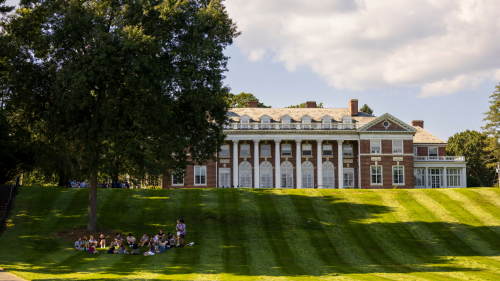 Students sitting in circle by tree in front of Donahue Hall.