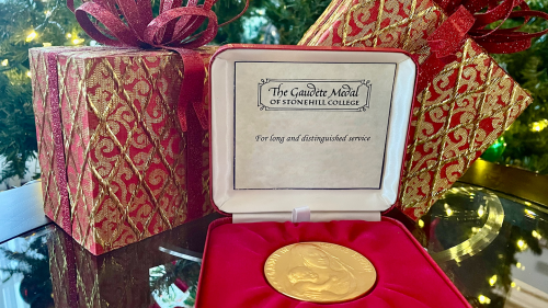Gaudete Medal for long and distinguished service in front of Christmas gifts and tree.