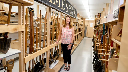 Nicole Casper '95 poses in front of the Ames Shovel collection, located in Cushing-Martin.