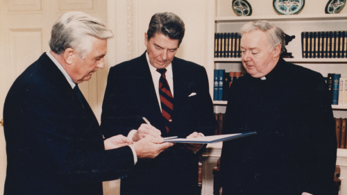 Bartley MacPhaidin (right) with President Ronald Reagan (center) and an unidentified man in the Oval Office, looking over documents.