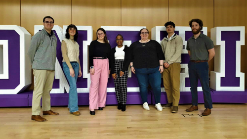 The 2023–2024 Student Government Association Executive Board on stage of McCarthy Auditorium, with giant letters spellling out Stonehill in the background