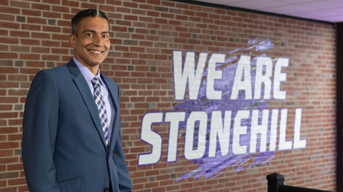 Stanley Thangaraj in front of "We Are Stonehill" sign.