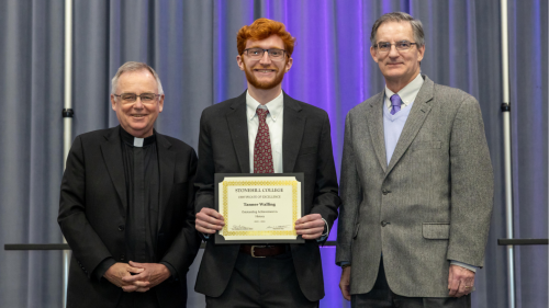 President John Denning, C.S.C. (left) and Professor John Rodrigue (right) present Tanner Walling '24 with a Certificate of Excellence at the 2024 Scholars Celebration.
