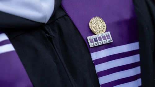 Two pins on a graduation sash, one that reads "Stonehill College First Generation."