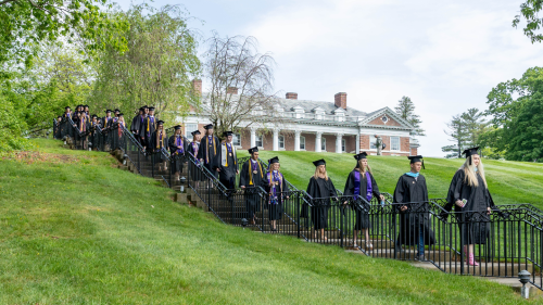 Stonehill graduates marching down stairs in front of Donahue Hall.