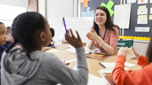 Teacher chatting with children in classroom.