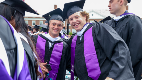 Two students in Commencement regalia, smiling
