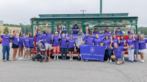 Student community members stand in group by trolley.