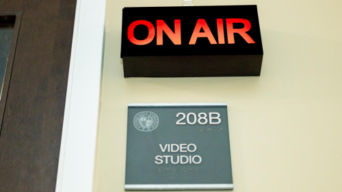 Red "on air" sign is lit up above another sign that reads "208B Video Studio"