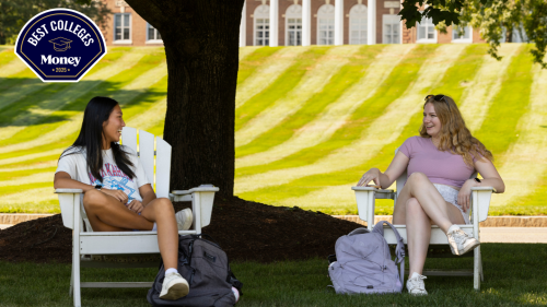 Two students sitting under a tree.