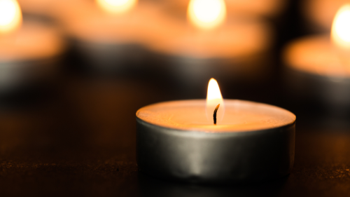 Lit candle glowing against a dark background.