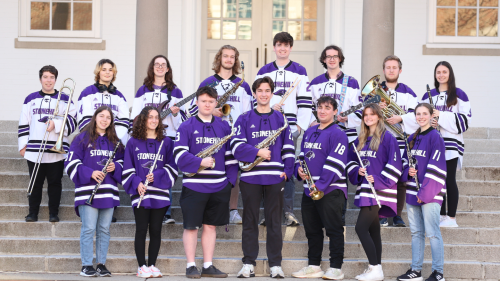 Members of the Screeching Skyhawk Athletic Band pose with their instruments in front of Cushing-Martin Hall. 