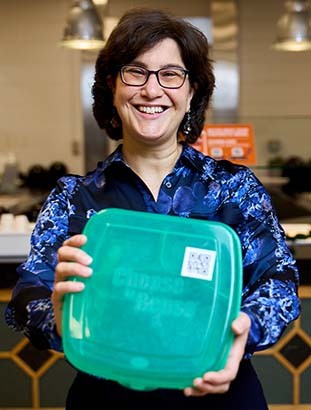 Professor and Chair of the Environmental Stewardship Council, Dr. Cheryl Schnitzer, holding plastic green food container