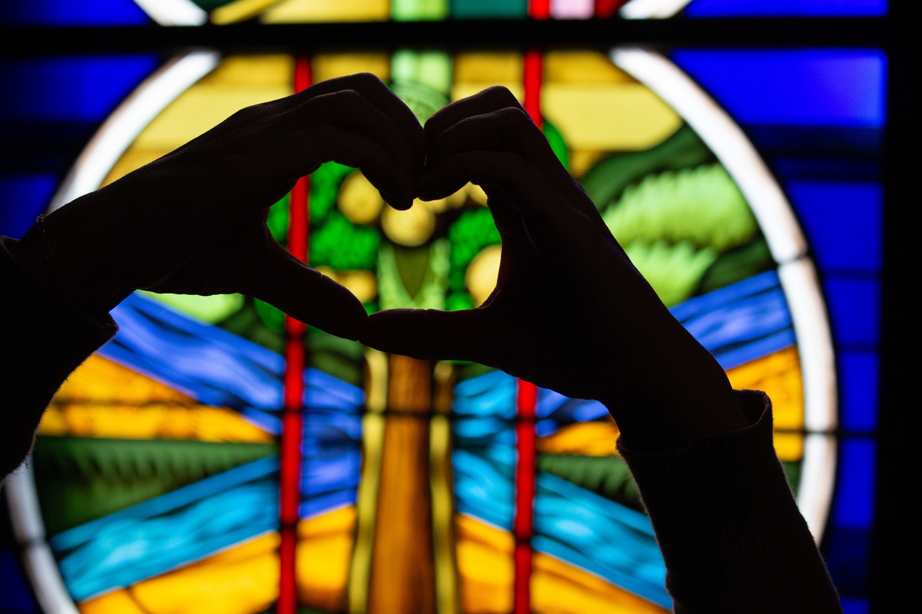 Hands in a heart over a stained glass window